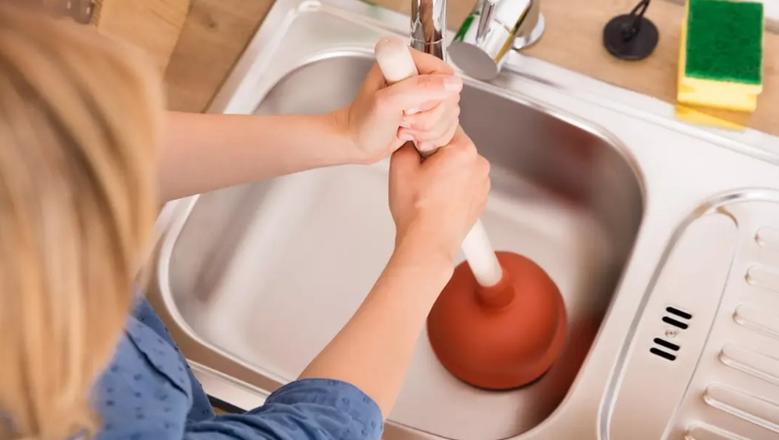 فني صحي يقوم بتسليك حوض المطبخ