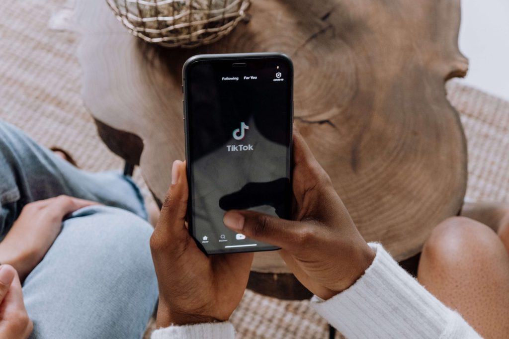 A person holding a phone with the TikTok app open