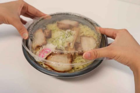 ラーメン容器を慎重に扱う様子