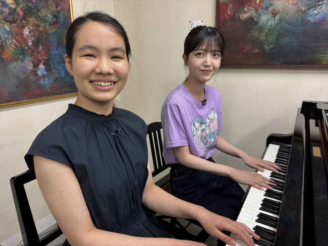 久保史緒里と少女がピアノの前に座る